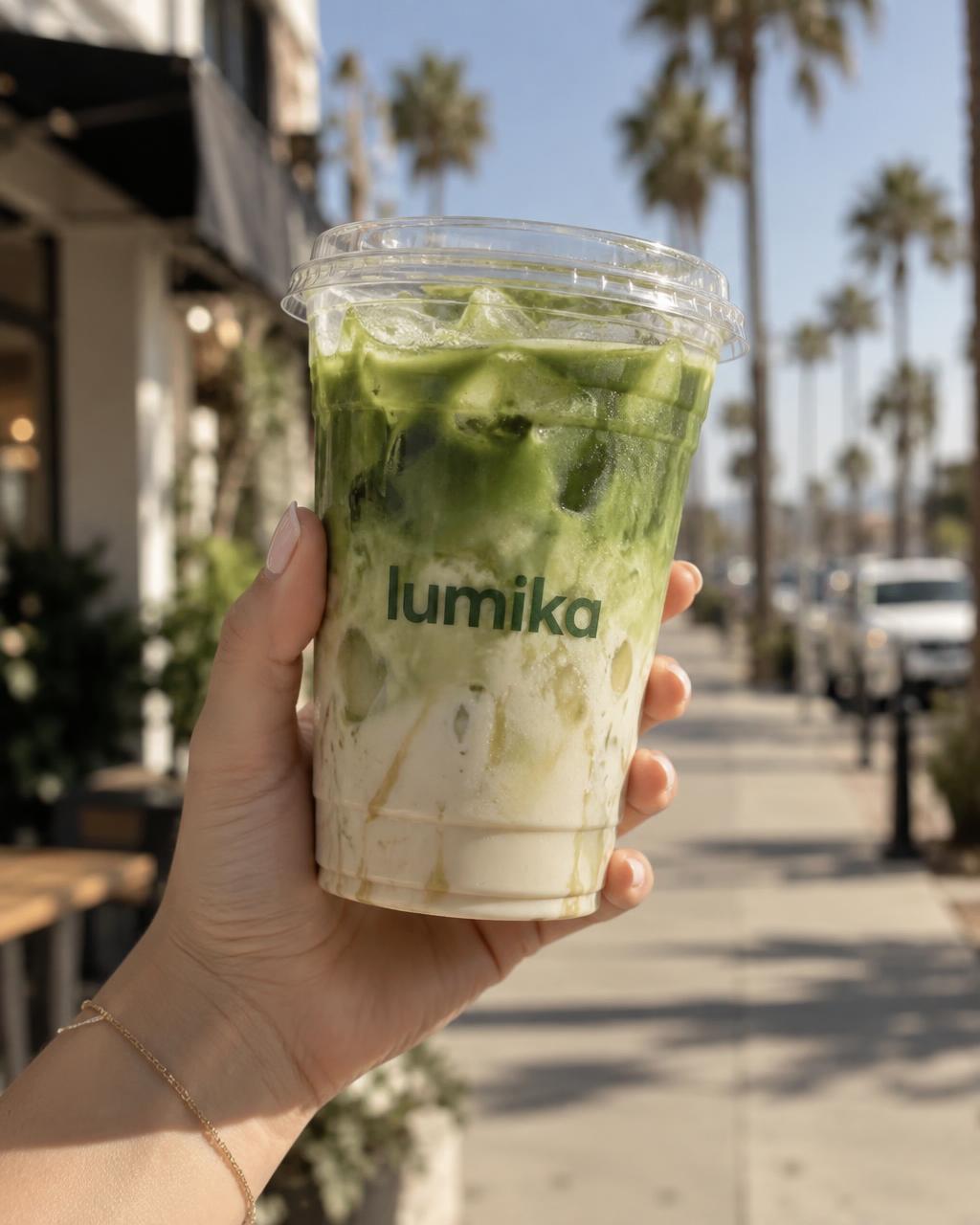 Hand holding an iced Inner Light matcha latte on a sunny San Diego sidewalk